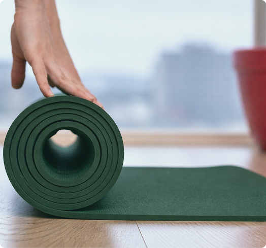 Main déroulant un tapis de yoga pour une séance de sophrologie et relaxation en entreprise